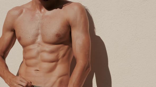 Handsome strong man with hot body posing outdoors near wall