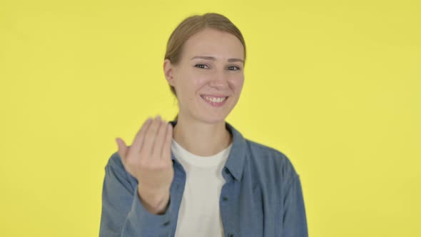 Young Woman Pointing at Camera Inviting on Yellow Background