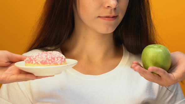 Cheerful Lady Choosing Green Apple Instead of Sweet Donut, Weight Loss, Close Up