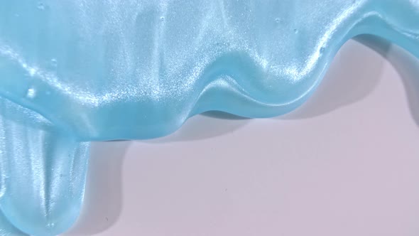 Blue Liquid Gel Cream with Micro Bubbles Flowing Down on a White Surface