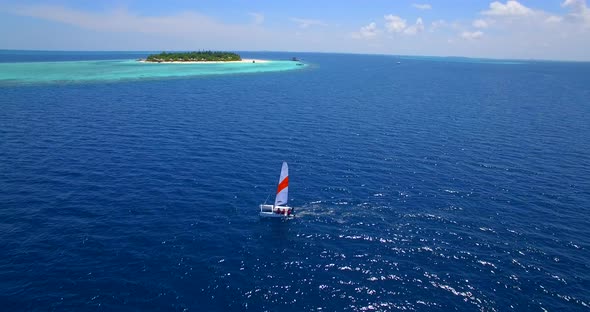 Aerial drone view of a man and woman sailing on a boat to a tropical island