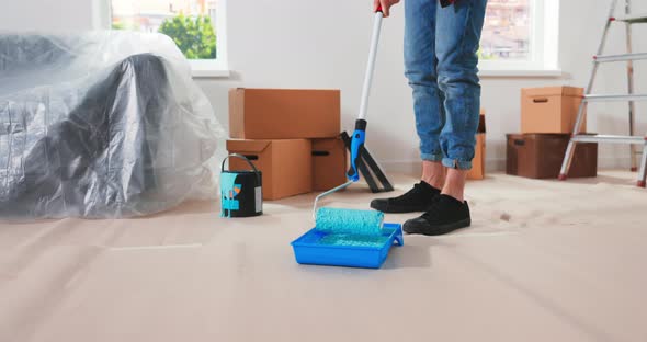 Caucasian Man Prepares for Repairs in New Apartment and Puts Roller in Container with Green