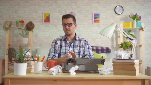 Young Man Writer Prints Without Inspiration on a Typewriter and Throwing the Paper