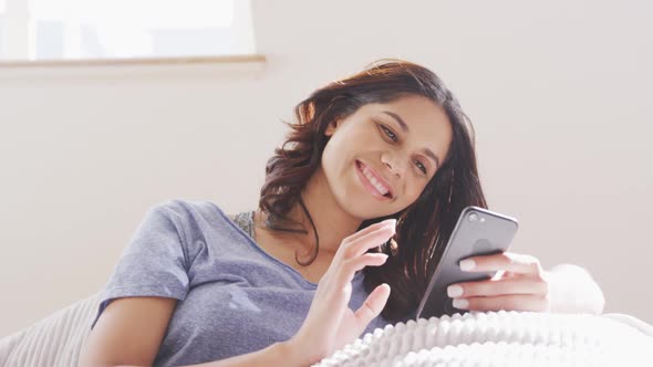 Cheerful woman adjusting her hair behind her ear while using smart phone