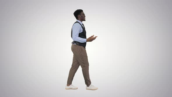 Young African American Businessman Gesturing and Talking To Camera While Walking on Gradient