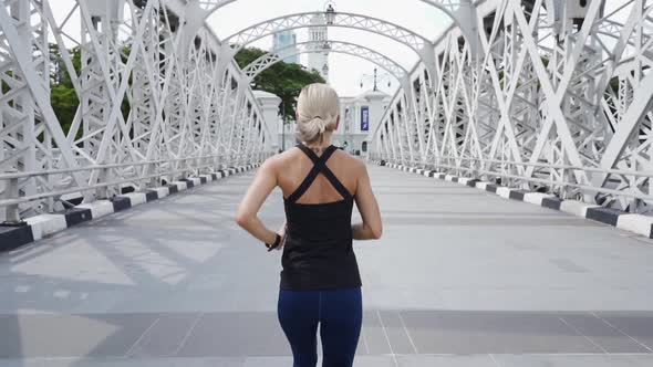 Young Asian Woman Runner Running on City Bridge Road with Cityscape on  Background