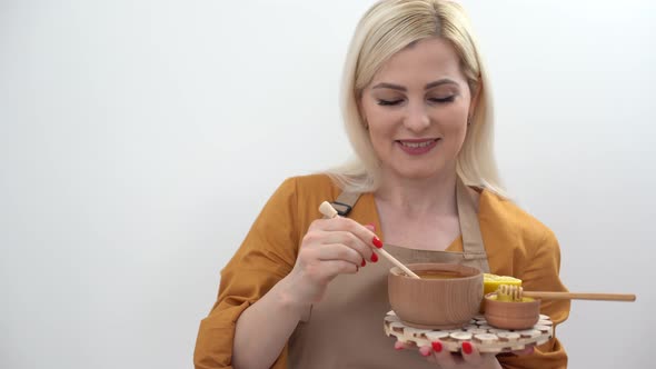 Smiling Young Woman with Bowl of Honey on White Background