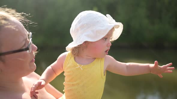 Little Cute Baby Toddler Girl Blonde with Curls on Mother's Arms