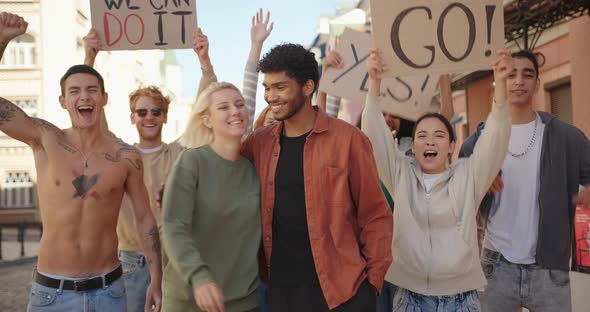 Multiracial Man and Woman Hug Each Other in Front of Multiethnic Protest Demonstration