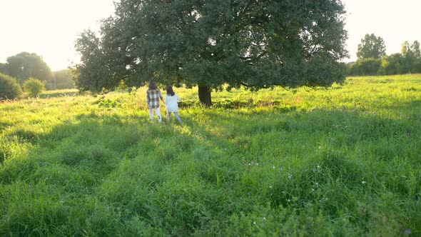 Happy young mum and daughter walking together outdoor enjoy beautiful field of sunshine