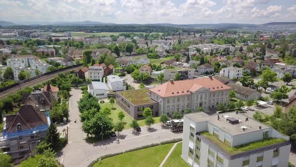 Drone shot over the city Bülach. A lot is going on, a bicycle is driving and a bus is passing by.