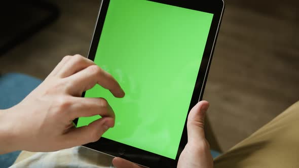 Close Up Hands of Young Guy at Home Resting on a Couch Using with Green Mockup Screen Tablet