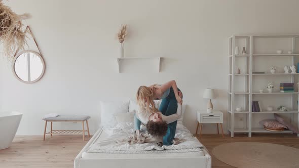 Young Teens Couple Dancing Jumping on Bed Mattress Active Carefree Hipster and Young Blonde Having