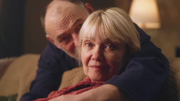 Elderly Husband Hugging Wife on Sofa