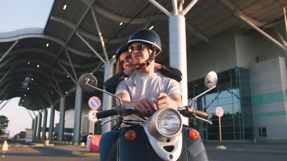 Happy Young Couple Riding Vintage Scooter on Urban Background and Having Some Fun Slow Motion