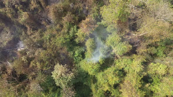 Smoke and burnt vegetation near green area drone shot