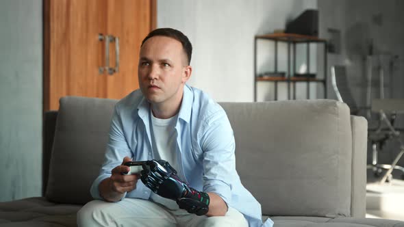 Concentrated guy with artificial high tech hand prothesis loses console game