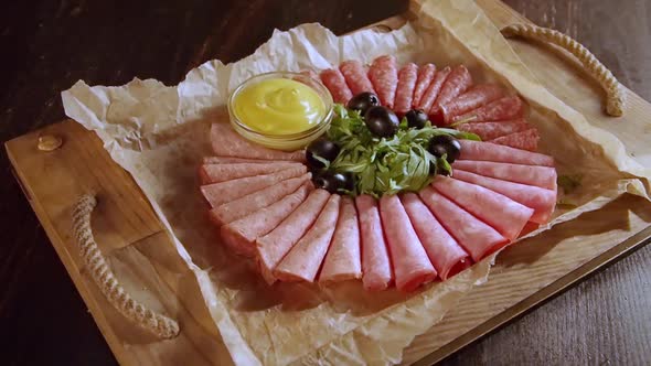 sausage cut with herbs and sauce on a wooden tray, beautiful serving, dark background