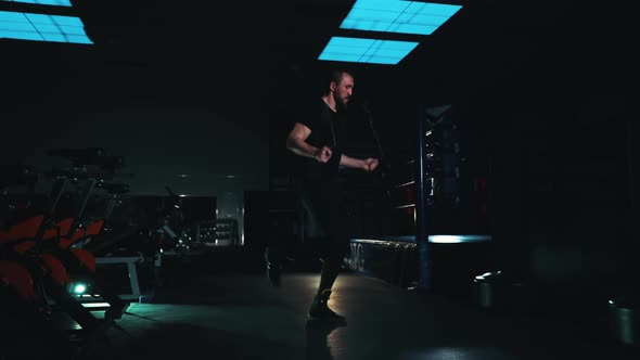 Fit Man Jumping on Rope in Dark Gym