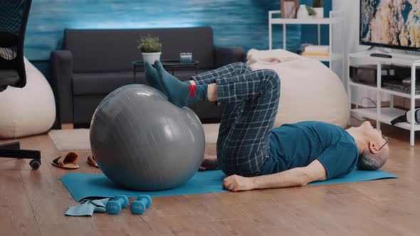 Retired Person Using Fitness Toning Ball and Lifting Legs