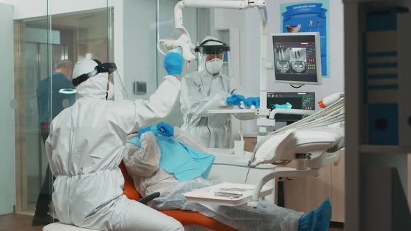 Doctor in Protective Suit Using Sterilized Dentl Tools