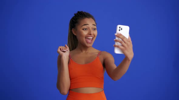 Smiling African girl with braid hairstyle talking by video call on the phone