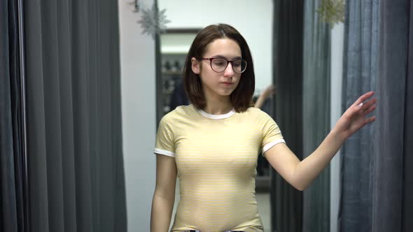 Young Woman Closes the Curtain in the Fitting Room. Clothing Store.