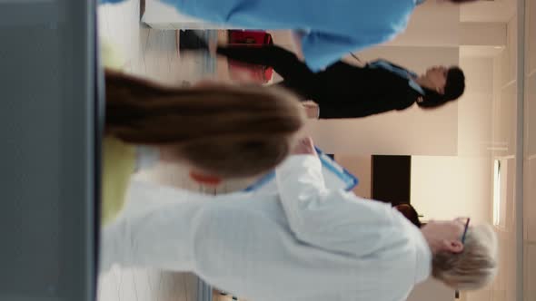 Vertical Video African American Physician Taking Mother with Child to Do Examination