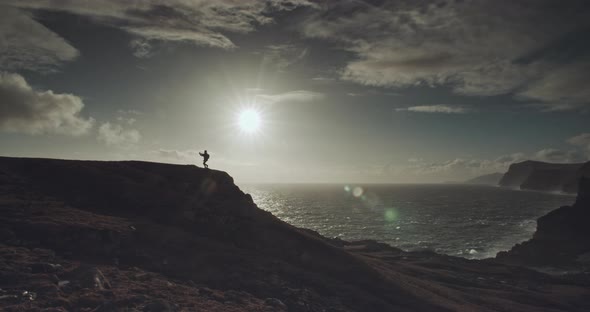 man walks along hilltop at sunset