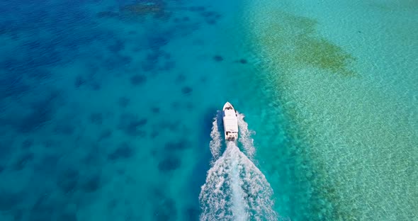 Aerial drone view of a motor boat going to a scenic tropical island in the Maldives