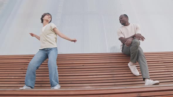 Multiethnic Couple Dancing on Bench Outdoors