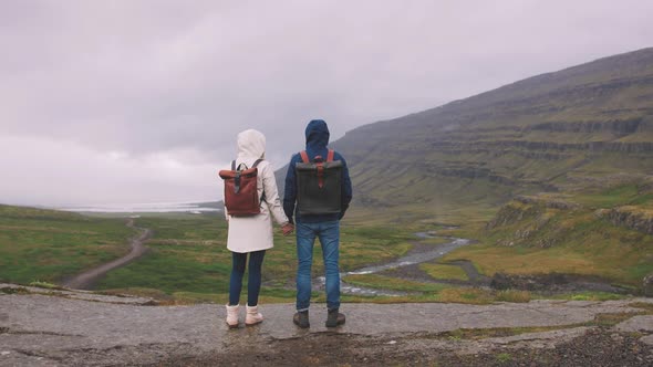 Young Couple with Leather Bags Enjoying Icelandic Landscape Backview