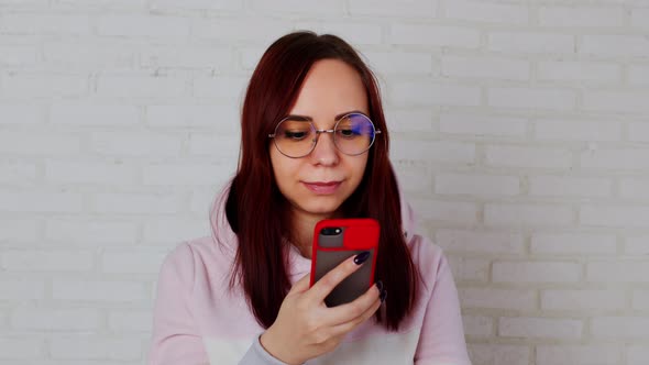 Young Woman Using Smartphone Near Wall