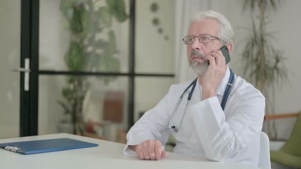 Senior Old Doctor Talking on Phone in Clinic