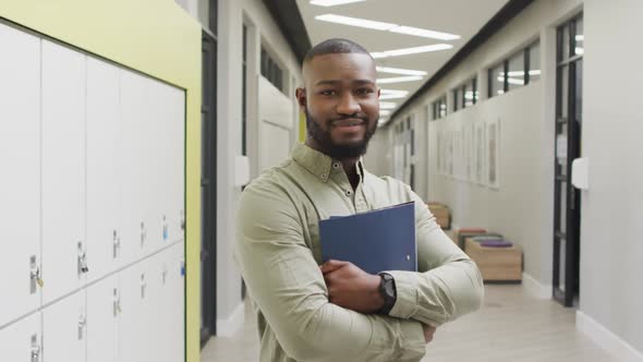 Video of happy african american male teacher standing in school hall alt