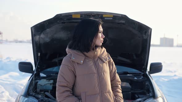 Upset Woman Shrugs Standing Near Broken Automobile in Field