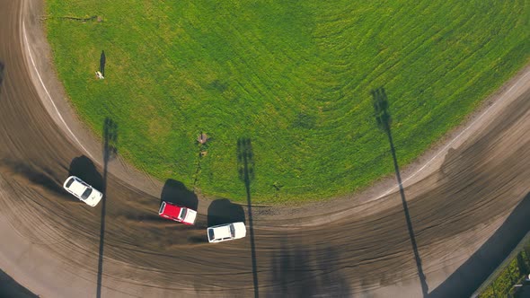 Aerial View on Top Races on the Racetrack. Cars Driving in a Circle Drifting Around Corners Compete