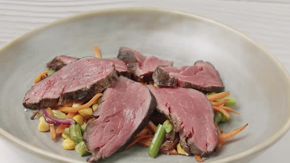 Close Up Grilled Vegetable Salad with Rare Medium Cooked Beef in a White Plate