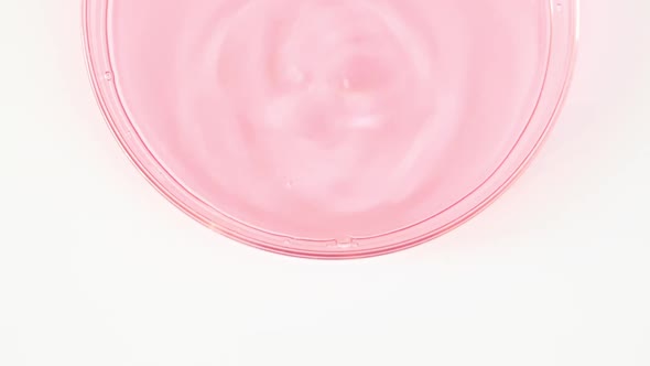 Transparent Pink Cosmetic Liquid Dripping in a Glass Bowl of Petri