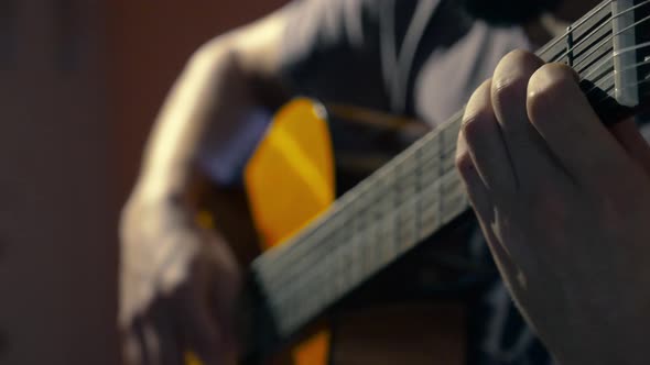 Male playing the guitar, strumming folk style chords