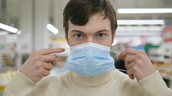 Coronovirus Covid-19. Portrait of Man Puts Medical Mask on His Face in a Supermarket