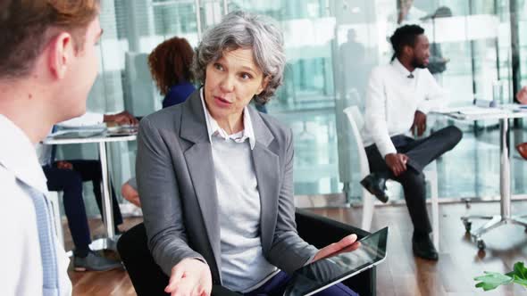 Businesswoman discussing over digital tablet with colleague