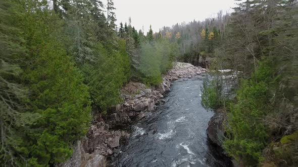 Aerial footage of a stream bends, mountains and autumn forest in Aguasabon Falls, Ontario, Canada