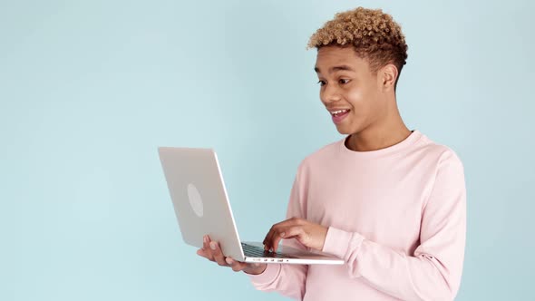 Excited Teenage Celebrating Good News on Laptop Against Blue Background