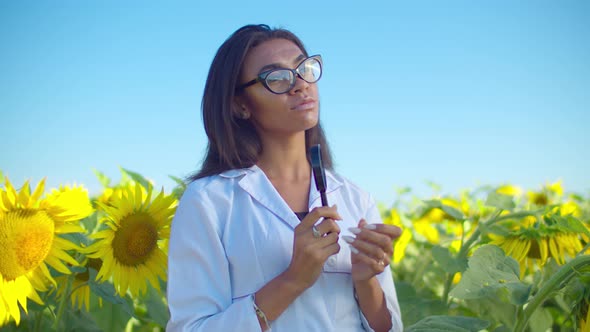 Pensive Black Woman Agronomist in Sunflower Field