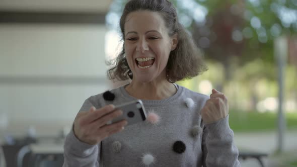 Emotional Middle Aged Woman Using Smartphone Outdoor