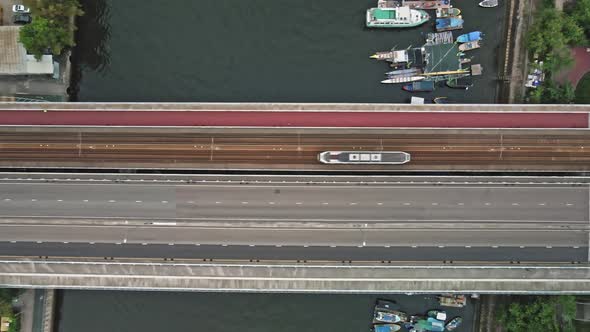 Aerial top down view of light rail crossing a bridge in Chinese city.