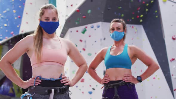 Portrait of two caucasian women wearing face masks standing at indoor climbing wall