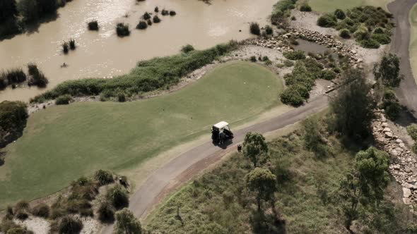 Flying back and tilting up to reveal a beautiful golf course hole with a large water hazard