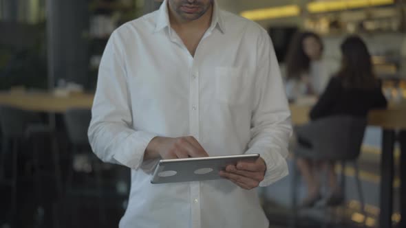 Unrecognizable Middle Eastern Businessman in White Shirt Messaging Online Using Tablet. Confident